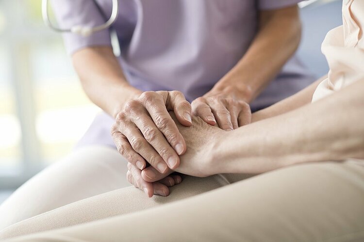 Care worker holding senior woman's hands.